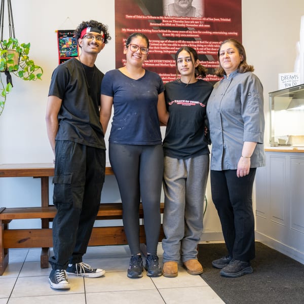 Four Taste of Trini staff members, including a chef, stand together in the restaurant.