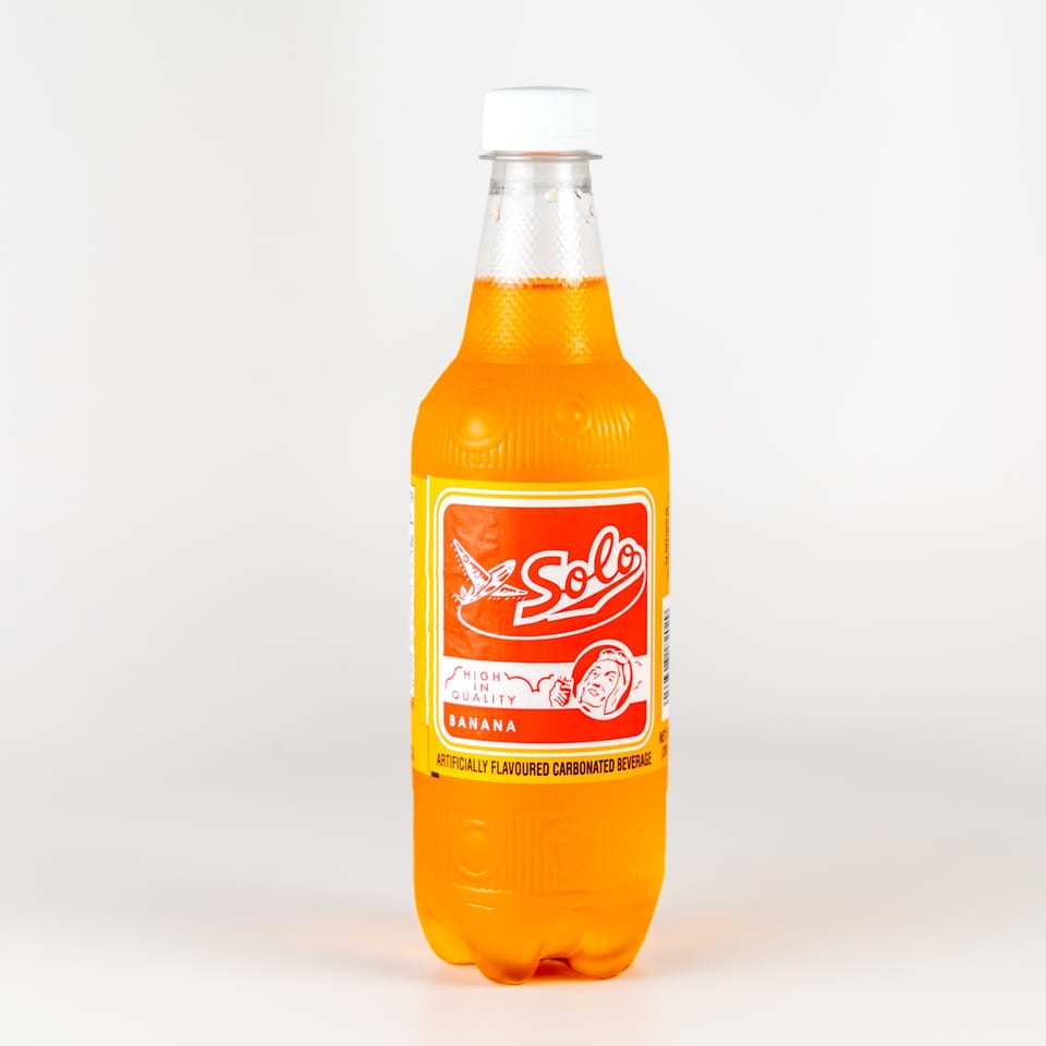 A Solo banana-flavored soda bottle, a popular Caribbean drink, with its distinctive red and yellow label.