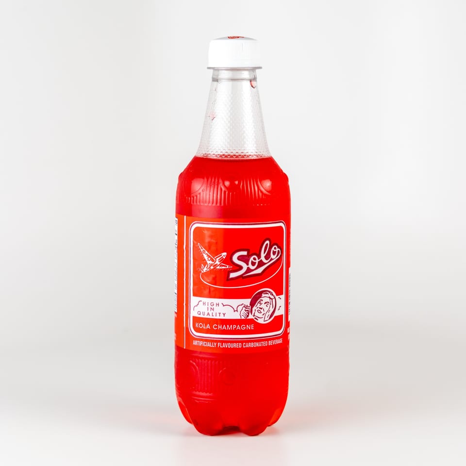 A bottle of Solo Kola Champagne, a red Caribbean soda, against a white background.